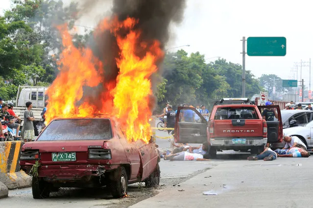 A car burns while mock victims lie on a main road during an earthquake drill as part of the joint capability demonstration of the Philippine Armed Forces' Reserve Command along with other government agencies in observance of national disaster consciousness month in Taguig city, metro Manila, Philippines July 30, 2016. (Photo by Romeo Ranoco/Reuters)
