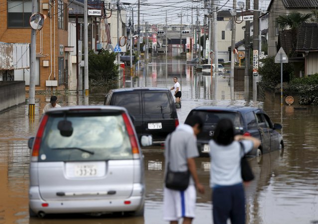 Local residents wade through a residential area flooded by the Kinugawa river, caused by typhoon Etau, at Mitsukaido district in Joso, Ibaraki prefecture, Japan, September 12, 2015. (Photo by Issei Kato/Reuters)
