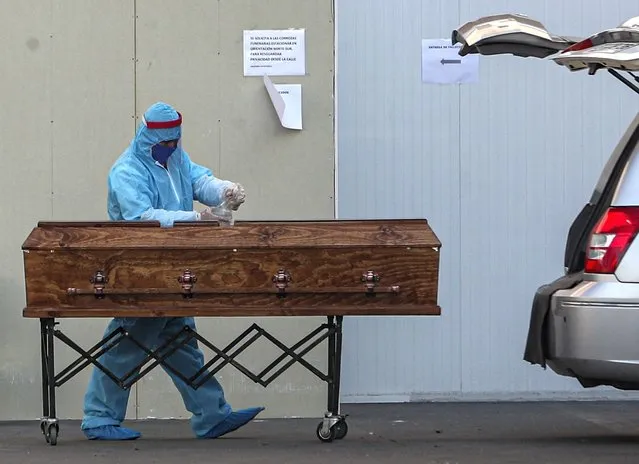 A funeral worker wearing protective gear as a precaution against the spread of the new coronavirus, sprays disinfectant on a coffin that contains the remains of person who died from the new coronavirus, at the San Jose hospital in Santiago, Chile, Tuesday, May 26, 2020. (Photo by Esteban Felix/AP Photo)