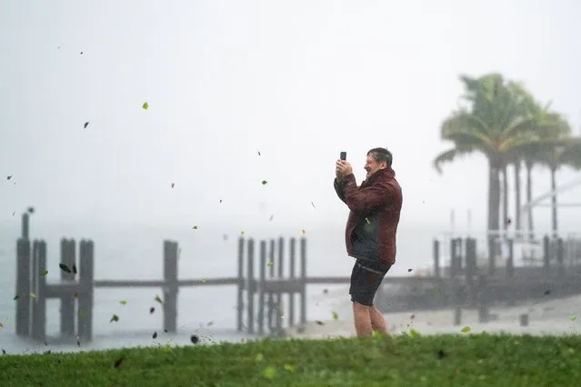 Peter Currin documents the weather at Sarasota Bay as a gust of wind carries leaves and debris while Hurricane Ian approaches on September 28, 2022 in Sarasota, Florida. Forecasts call for the storm to make landfall in the area on Wednesday as a likely Category 4 hurricane. (Photo by Sean Rayford/Getty Images)