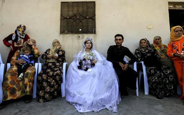 A picture taken on October 27, 2017 shows the groom Ahmed (C- R) and bride Heba (C- L) seated during the first wedding after the ouster of the Islamic State (IS) group from the eastern city of Raqa, in the western suburb of Jazra, Syria. (Photo by Delil Souleiman/AFP Photo)