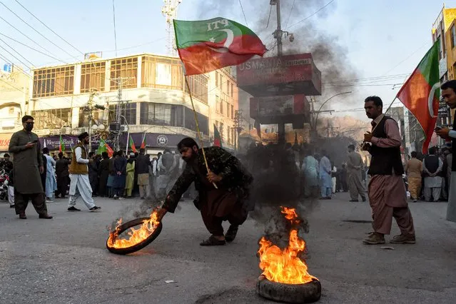 Activists of Pakistan Tehreek-e-Insaf (PTI) party burn tyres during a protest against the disqualifying decision of former prime minister Imran Khan on a street in Quetta on October 21, 2022. Former Pakistan prime minister Imran Khan was disqualified October 21, from running for political office for five years, his lawyer said, after the country's election commission ruled he misled officials about gifts he received while in power. (Photo by Banaras Khan/AFP Photo)