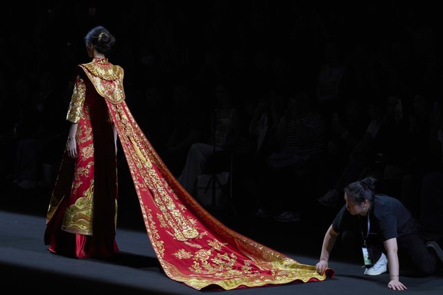 A staffer helps adjust the cape for a model during the show titled Tianxi by Juanjuan Su for China Fashion Week in Beijing, Friday, March 21, 2025. (Photo by Ng Han Guan/AP Photo)