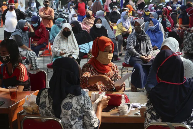 Residents keep social distancing as a precaution against the new coronavirus outbreak as they queue up for free staple food packages provided by the government for low-income residents in Jakarta, Indonesia Thursday, June 11, 2020. (Photo by Achmad Ibrahim/AP Photo)