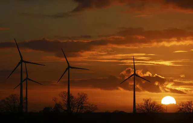 The sun sets behind wind turbines near Pokrent, northern Germany, Friday, November 17, 2017. (Photo by Jens Buettner/DPA via AP Photo)