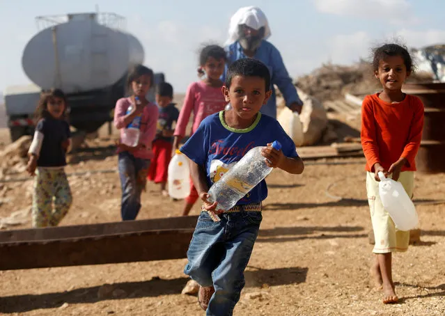 Palestinian children carry water bottles near their house on the outskirts of the West Bank village of Yatta, south of Hebron, August 17, 2016. (Photo by Mussa Qawasma/Reuters)