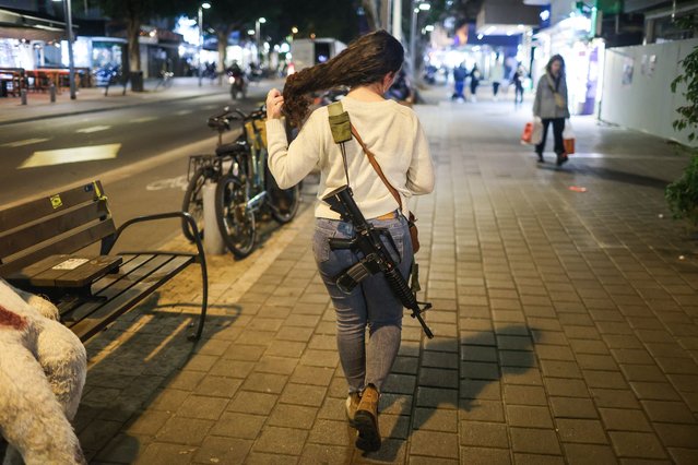 A woman carries an assault rifle on Dizengoff Street in Tel Aviv, Israel. 18 January 2024. Since the 07 October 2023 Hamas attacks, the Israel Defense Forces (IDF) has recruited more than 300,000 reservists soldiers, while over 260,000 new applications for weapons licenses have been submitted to the Ministry of Internal Security office, the minister of national security said. The events of October 2023 had a huge impact on Israeli citizens and their sense of personal security. (Photo by Abir Sultan/EPA/EFE)