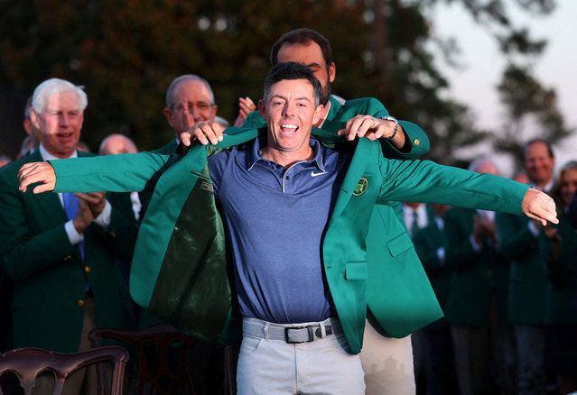 Northern Ireland's Rory McIlroy is presented with the green jacket by Scottie Scheffler of the U.S. after winning The Masters and completing a career grand slam on April 14, 2025. (Photo by Mike Segar/Reuters)