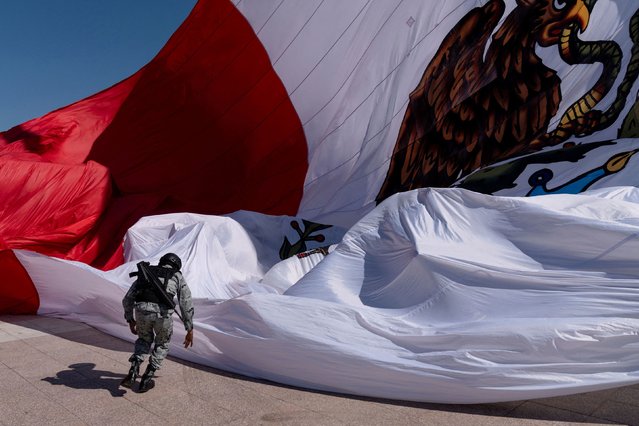 A member of the Mexican National Guard races to secure a giant national flag after members of the military lost their grip as it was unfurled during Flag Day, in Piedras Negras, Coahuila, Mexico, on February 24, 2024. (Photo by Cheney Orr/Reuters)