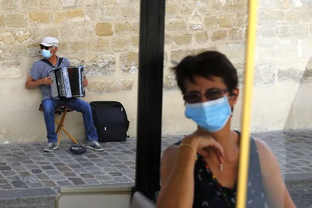 An accordionist wearing a face mask performs in the Montmartre district Monday, August 10, 2020 in Paris. People are required to wear a mask outdoors starting on Monday in the most frequented areas of the French capital. The move comes as the country sees an uptick in virus infections. (Photo by Michel Euler/AP Photo)