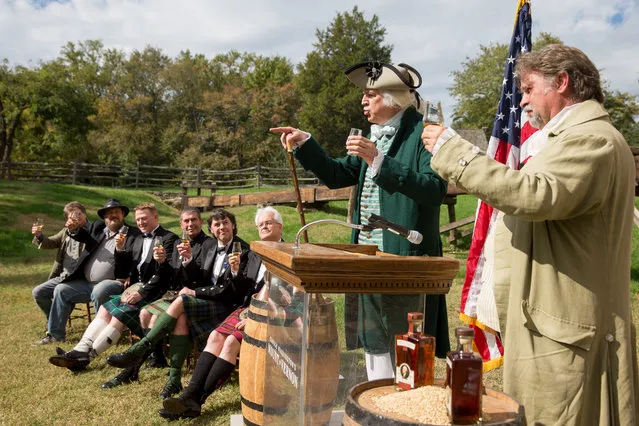 Whisky distillers including Scottish master distillers watch as Dean Malissa of Philadelphia, historical portrayer of George Washington, second from right, toast the first single malt whisky produced at George Washington's Distillery, Tuesday, October 13, 2015, in Mount Vernon, Va. After a three-year aging process, distillers at George Washington's Mount Vernon estate tasted a batch of single malt whisky made at the estate's distillery. (Photo by Andrew Harnik/AP Photo)