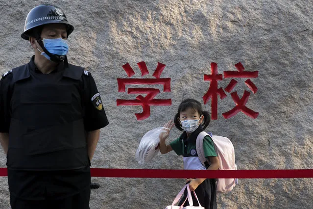 A student wearing a face mask to help curb the spread of the coronavirus waves next to a masked security guard as she arrives to a primary school in Beijing, Monday, September 7, 2020. Students in the capital city returned to school on Monday in a staggered start to the new school year because of the coronavirus outbreak. (Photo by Andy Wong/AP Photo)