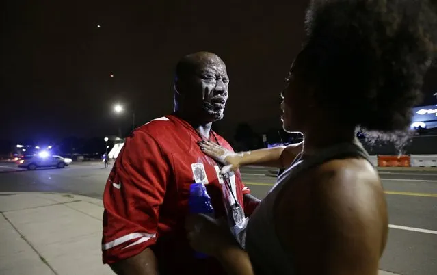 A man is assisted after being sprayed by police during a confrontation with protesters that were blocking I-277 in uptown during protests following Tuesday's police shooting of Keith Lamont Scott in Charlotte, N.C., Thursday, September 22, 2016. (Photo by Gerry Broome/AP Photo)