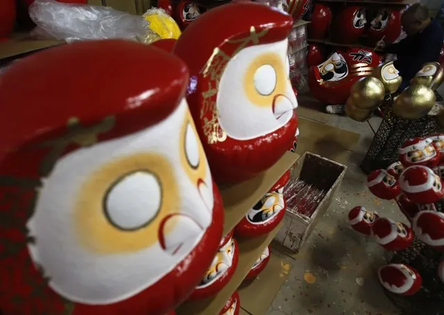 Japanese craftsman Sumikazu Nakata adds the final touches on a Daruma doll, which is believed to bring good luck, at his studio  “Daimonya” in Takasaki, northwest of Tokyo November 23, 2014. (Photo by Yuya Shino/Reuters)