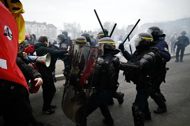 French CRS riot police brandich their batons in front of protesters durng clashes on a second day of nationwide strikes and protests over the government's proposed pension reform, in Nantes on January 31, 2023. France braces for major transport blockages, with mass strikes and protests set to hit the country for the second time in a month in objection to the planned boost of the age of retirement from 62 to 64. On January 19, some 1.1 million voiced their opposition to the proposed shake-up – the largest protests since the last major round of pension reform in 2010. (Photo by Loic Venance/AFP Photo)