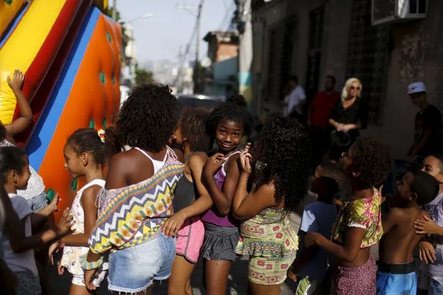 Kids wait in line to enter a bouncy castle during an event to celebrate the upcoming Children's Day at Providencia slum in Rio de Janeiro, Brazil, October 9, 2015. The event was organized by the Police Peacekeeping Unit (UPP). (Photo by Pilar Olivares/Reuters)