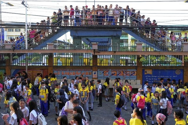 Parents and guardians look from a bridge outside an elementary school during the opening of the new school year in Quezon city, Philippines on Monday, June 16, 2025. (Photo by Aaron Favila/AP Photo)