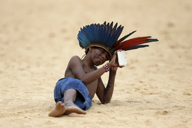 An indigenous boy from the Mamaind tribe uses a tablet during the Jikunahati competition, a form of soccer played with one's head, at the first World Games for Indigenous Peoples in Palmas, Brazil, October 29, 2015. (Photo by Ueslei Marcelino/Reuters)