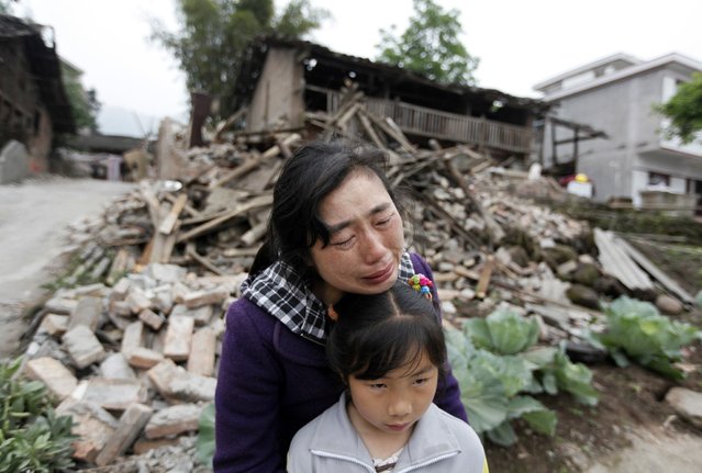 Song Zhengqiong, holding her daughter, cries in front of her damaged house after a strong 6.6 magnitude earthquake at Longmen village, Lushan county in Ya'an, Sichuan province April 21, 2013. Rescuers poured into a remote corner of southwestern China on Sunday as the death toll from the country's worst earthquake in three years climbed to 164 with more than 6,700 injured, state media said. (Photo by Jason Lee/Reuters)