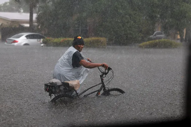 A person walks his bike through a flooded street on April 13, 2023 in Fort Lauderdale, Florida. Nearly 26 inches of rain fell on Fort Lauderdale over a 24-hour period, with more expected throughout the day, according to the National Weather Service. Fort Lauderdale-Hollywood International Airport traffic is closed until 5 a.m. Friday. (Photo by Joe Raedle/Getty Images)