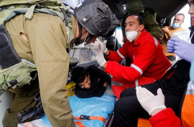 An Israeli soldier attempts to detain a wounded Palestinian demonstrator lying in an ambulance during a protest against Jewish settlements in Jordan Valley in the Israeli-occupied West Bank on November 24, 2020. (Photo by Raneen Sawafta/Reuters)