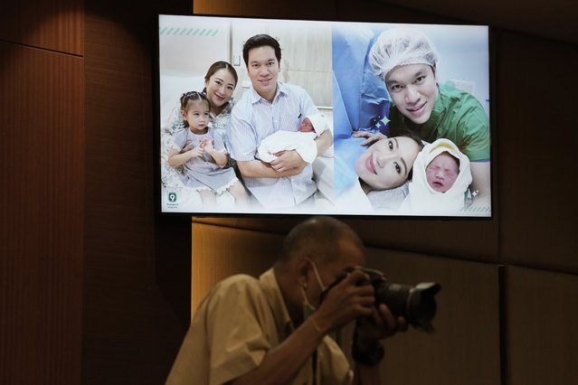 A Thai photographer takes picture under television showing Paetongtarn Shinawatra, Pheu Thai party's top politician and youngest daughter of exiled former deposed Thai leader Thaksin Shinawatra and her husband Pidok Sooksawas with her new born son at press conference in Bangkok, Thailand, Wednesday, May 3, 2023. The frontrunning candidate for prime minister of Thailand said Wednesday she’s eager to get back on the campaign trail, just two days after giving birth. (Photo by Sakchai Lalit/AP Photo)