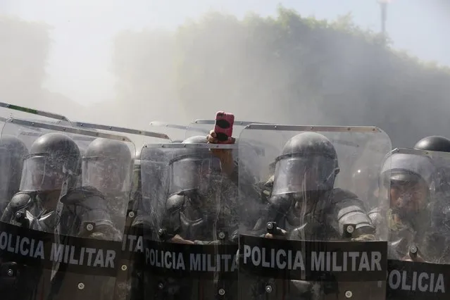 A military police officer records with a cell phone, amid smoke, during a demonstration by activists and relatives of the 43 missing trainee teachers from Ayotzinapa Teacher Training College, in the military zone of the 27th infantry battalion, in Iguala, Guerrero, January 12, 2015. (Photo by Jorge Dan Lopez/Reuters)