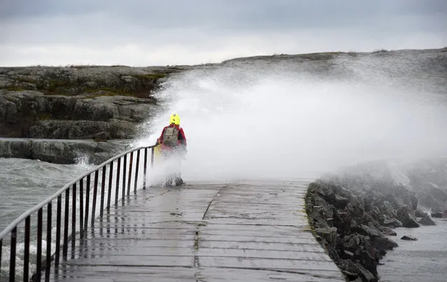 A woman is hit by a wave caused by stormy winds in Helsinki, on November 30, 2015. (Photo by Markku Ulander/AFP Photo)