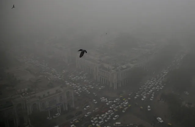 Traffic moves around a smog-enveloped Connaught Place, the heart of New Delhi, India, Saturday, November 5, 2016. According to one advocacy group, government data shows that the smog that enveloped New Delhi this past week was the worst in the last 17 years. The concentration of PM2.5, tiny particulate pollution that can clog lungs, averaged close to 700 micrograms per cubic meter. That's 12 times the government norm and a whopping 70 times the WHO standards. (Photo by Altaf Qadri/AP Photo)