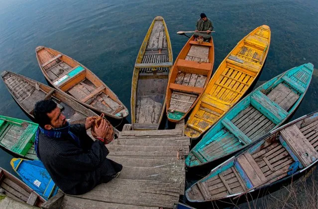 A boatman rows his boat, as a man sits on a dock, in the Dal Lake, December 14, 2015, in Srinagar, India. Kashmir is known as “Paradise on Earth” and has for centuries captured the imagination of many writers, poets and film makers. Kashmir has been a contested land between nuclear neighbors India and Pakistan since 1947, the year both the countries attained freedom from British rule. (Photo by Yawar Nazir/Getty Images)