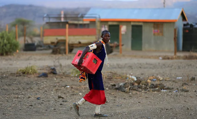 A Maasai tribeswoman carries a crate of soda as she and her community prepare to witness the rise of the supermoon in Oloika village in Shompole, Magadi near the Kenya-Tanzanian border, November 14, 2016. (Photo by Thomas Mukoya/Reuters)