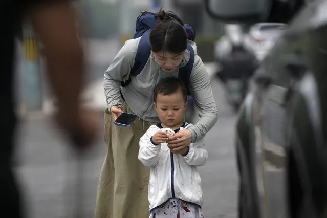 A woman helps a child to switch on an electric fan on a hot day in Beijing, Monday, July 3, 2023. (Photo by Andy Wong/AP Photo)