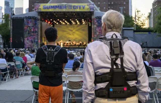 Concertgoers wear haptic suits created for the deaf by Music: Not Impossible, during an outdoor concert at Lincoln Center on July 22, 2023, in New York City. The violins reverberate in the ribcage, while cello and bass are felt a little further down, with horns in the shoulders, and more often than not, soloists in the wrists. That's one way audio expert Patrick Hanlon programs wireless haptic suits designed to enable the deaf or hard of hearing to experience orchestral music, as initiatives to improve inclusivity at live music performances break new ground. At the Lincoln Center concert, audience members tried vests featuring 24 points of vibration that translate the music onstage. (Photo by Angela Weiss/AFP Photo)