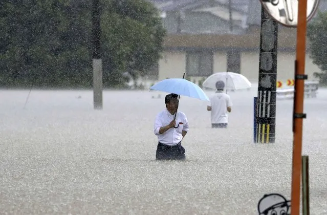 People wade through a street due to a heavy rain in Kurume, Fukuoka prefecture, southern Japan Monday, July 10, 2023. Torrential rain has been pounding southwestern Japan, triggering floods and mudslides. (Photo by Kyodo News via AP Photo)