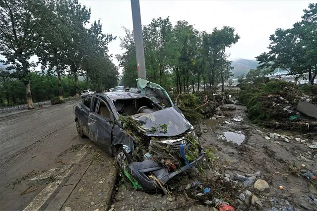 A damaged car is pictured along a road following heavy rains in Fangshan district in Beijing on August 1, 2023. (Photo by Pedro Pardo/AFP Photo)