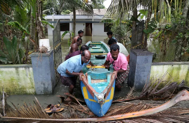 People push a boat through a gate of a flooded house at Kuttanad in Alleppey district in the southern state of Kerala, India, August 24, 2018. (Photo by Sivaram V/Reuters)