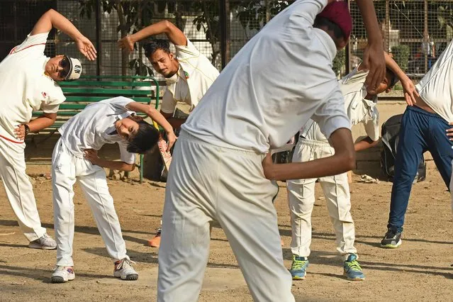Children do stretching exercises during a cricket practise session at a park in Amritsar on April 15, 2021. (Photo by Narinder Nanu/AFP Photo)