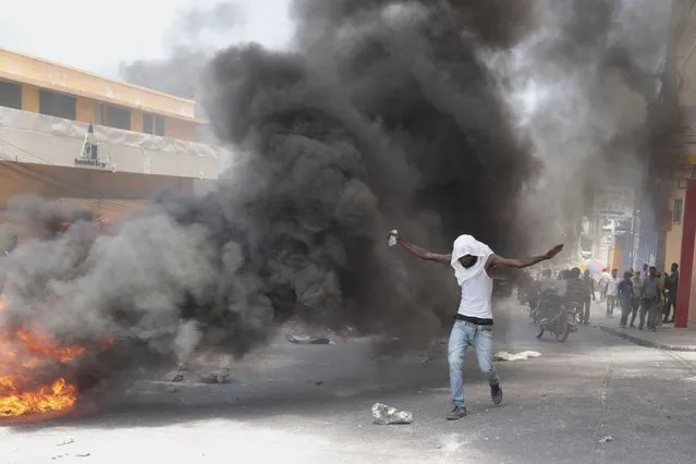 A protester walks past tires set fire by demonstrators protesting insecurity in Port-au-Prince, Haiti, Monday, August 7, 2023. (Photo by Joseph Odelyn/AP Photo)