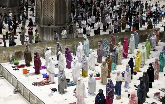 Indonesian Muslims pray spaced apart as they practice social distancing to curb the spread of the new coronavirus during an evening prayer called "tarawih" marking the first eve of the holy fasting month of Ramadan at Istiqlal Mosque in Jakarta, Indonesia. Monday, April 12, 2021. During Ramadan, the holiest month in Islamic calendar, Muslims refrain from eating, drinking, smoking and s*x from dawn to dusk. (Photo by Achmad Ibrahim/AP Photo)