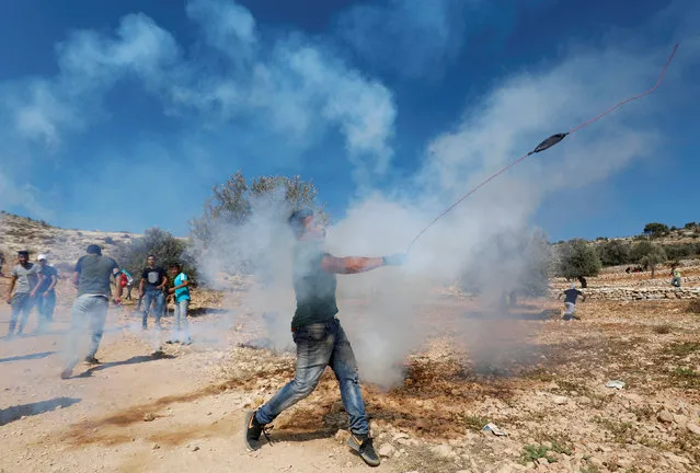 A Palestinian demonstrator hurls stones at Israeli troops during a protest against Israeli land seizures for Jewish settlements, in the village of Ras Karkar, near Ramallah in the occupied West Bank September 28, 2018. (Photo by Mohamad Torokman/Reuters)