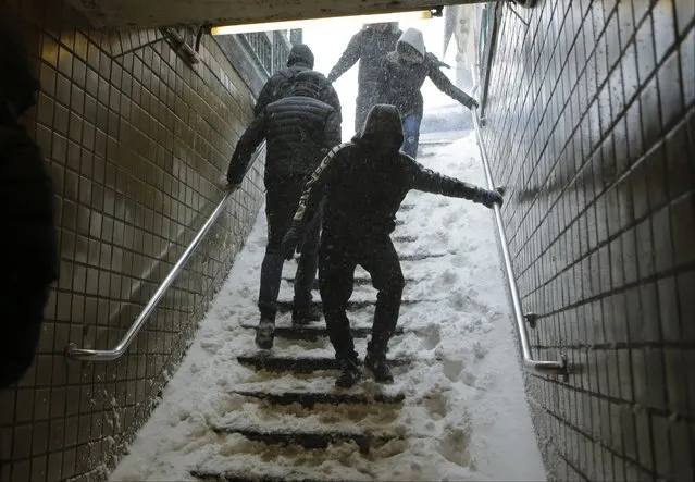 Travelers navigate snow covered steps at the Union Turnpike subway station in the Queens borough of New York during a snowstorm Saturday, January 23, 2016. New York Gov. Andrew Cuomo has announced a travel ban in New York City and on Long Island, saying all non-emergency vehicles should be off New York City's roads after 2:30 p.m. Saturday. (Photo by Frank Franklin II/AP Photo)