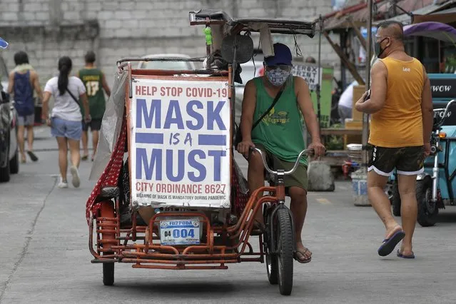 A man rides his pedicab with a slogan to remind people to wear masks to prevent the spread of the coronavirus in Manila, Philippines on Monday, April 26, 2021. COVID-19 infections in the Philippines surged past 1 million Monday in the latest grim milestone as officials assessed whether to extend a monthlong lockdown in Manila and outlying provinces amid a deadly spike or relax it to fight recession, joblessness and hunger. (Photo by Aaron Favila/AP Photo)