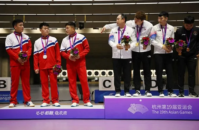 Asian Games shooting gold medallists South Korea's Ha Kwang-chul, Jeong You-jin and Your Bin Kwak stand on the podium after the Men's Team 10m Running Target Mixed event alongside silver medallists North Korea's Kwon Kwang-il, Pak Myong-won and Songjun Yu in Hangzhou, China on September 25, 2023. (Photo by Dylan Martinez/Reuters)