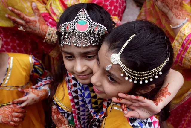 Children with traditional jewelry hug each other during Eid al-Adha celebration in Lahore, Pakistan on August 22, 2018. (Photo by Mohsin Raza/Reuters)