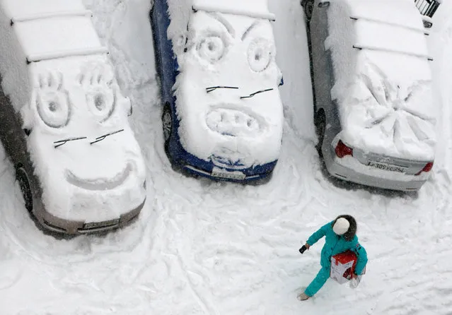 A woman walks past cars with faces which are scrawled on windows covered with snow during snowfall in Krasnoyarsk, Russia November 5, 2018. (Photo by Ilya Naymushin/Reuters)