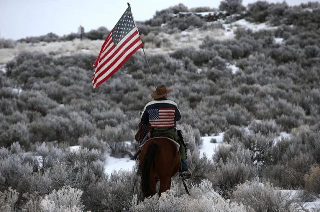 Dwayne Ehmer carries an American flag as he rides his horse on the Malheur National Wildlife Refuge  on January 7, 2016 near Burns, Oregon.  An armed anti-government militia group continues to occupy the Malheur National Wildlife Headquarters as they protest the jailing of two ranchers for arson. (Photo by Justin Sullivan/Getty Images)
