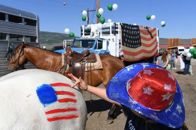 Aida Hester paints an American flag on a horse before taking part in a Fourth of July parade on Sunday July 04, 2021 in Granby, CO. (Photo by Matt McClain/The Washington Post)