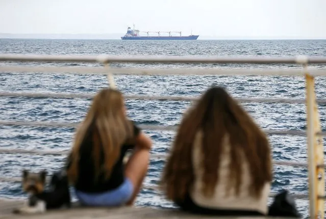 People watch Sierra Leone-flagged cargo ship 'Razoni' leave the port of Odesa, Ukraine, 01 August 2022. The Razoni carries over 26,000 tons of corn and is bound for Tripoli, Lebanon with a stopover in Istanbul for inspection. It is the first ship exporting Ukrainian grain since a safe passage deal was signed between Ukraine and Russia on 22 July in Istanbul. Russian troops on 24 February entered Ukrainian territory, starting a conflict that has provoked destruction and a humanitarian crisis. (Photo by EPA/EFE/Stringer)
