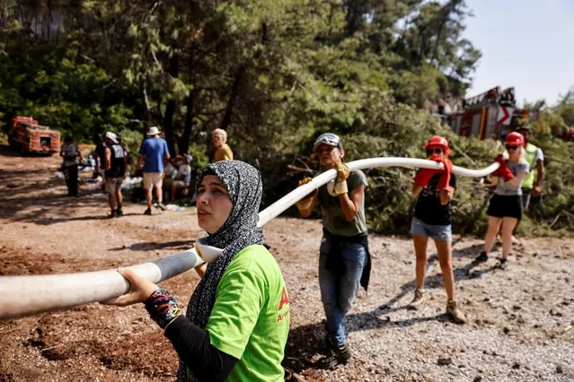 Volunteers hold a hose while trying to extinguish a wildfire near Marmaris, Turkey, August 3, 2021. (Photo by Umit Bektas/Reuters)