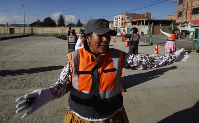 In this November 28, 2013 photo, an Aymara woman cops practices hand-and-arm signals for directing traffic during a training session in El Alto, Bolivia. (Photo by Juan Karita/AP Photo)